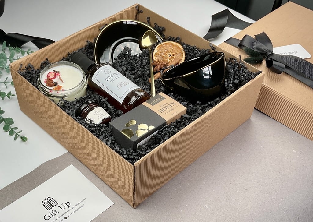 prezent box kosz upominek a w środku czarna elegancka filiżanka porcelanowa ze złotym rantem idealna do kawy lub herbaty złota łyżeczka syrop karmelowy przepyszny konfitura malinowa z migdałami słodka krówka miodowa