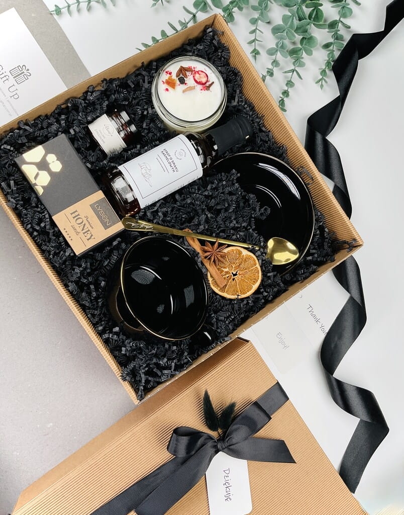 elegancki klasyczny ponadczasowy zestaw prezentowy ze słodyczami naturalną świecą sojową o zapachu grzane wino słodką krówką miodową syropem karmelowym czarną elegancką filiżanką ze złotym rantem i złota łyżeczka