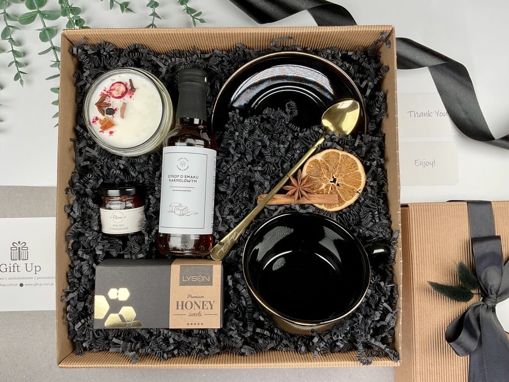 elegancki klasyczny ponadczasowy zestaw prezentowy ze słodyczami naturalną świecą sojową o zapachu grzane wino słodką krówką miodową syropem karmelowym czarną elegancką filiżanką ze złotym rantem i złota łyżeczka