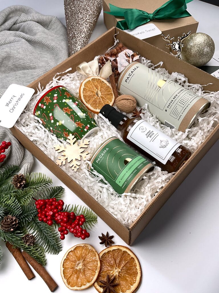Elegancki świąteczny box prezentowy: świąteczny porcelanowy kubek, kawa ziarnista premium w puszce, przepyszny agrest w belgijskiej czekoladzie, aromatyczny syrop pumpkin spice i orzeszki w miodzie i karmelu. Idealny prezent bożonarodzeniowy.