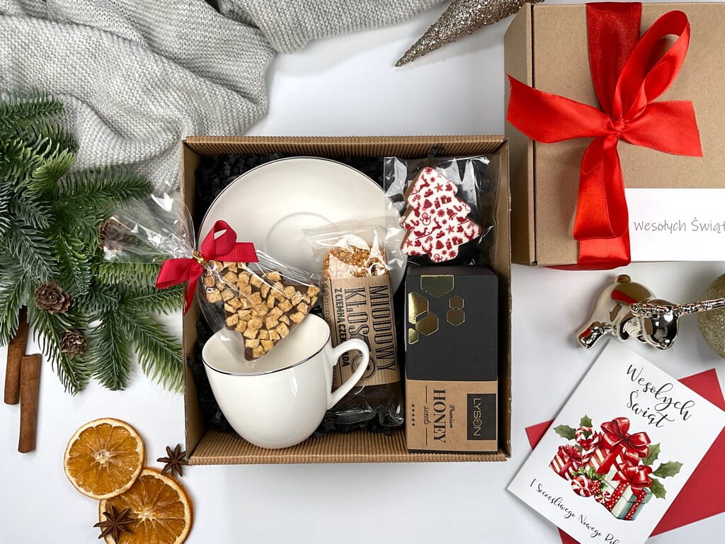 Świąteczny box prezentowy z porcelanową filiżanką, mleczną czekoladą choinką z jabłkiem i cynamonem, batonem miodowym kłos, krówką miodową i ozdobnym pierniczkiem. Idealny prezent na Mikołajki.