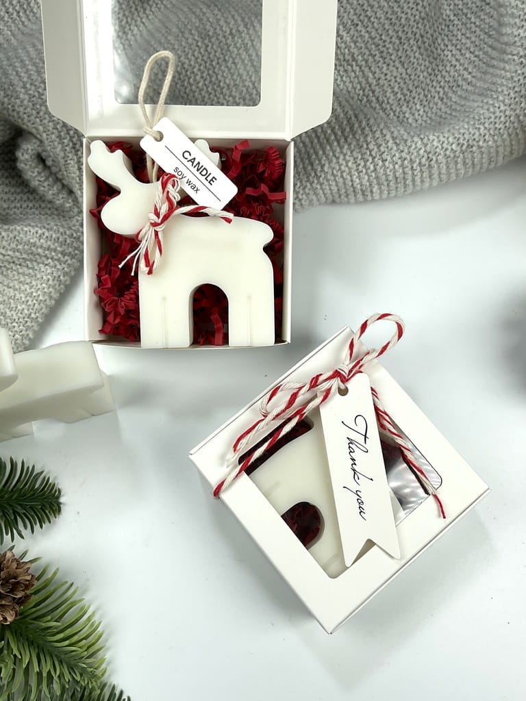 Mini box z naturalną świecą sojową w kształcie renifera, ozdobnym pudełkiem z okienkiem, kokardką i bilecikiem. Mały, elegancki prezent na Mikołajki i święta.