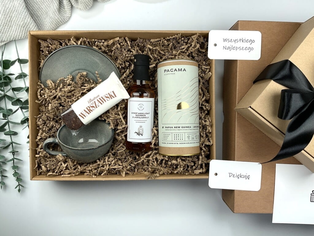 Zestaw prezentowy z filiżanką kamionkową w czerni i zieleni, kawą ziarnistą premium, naturalnym batonem bezglutenowym i syropem waniliowym bourbon. Elegancki upominek świąteczny.