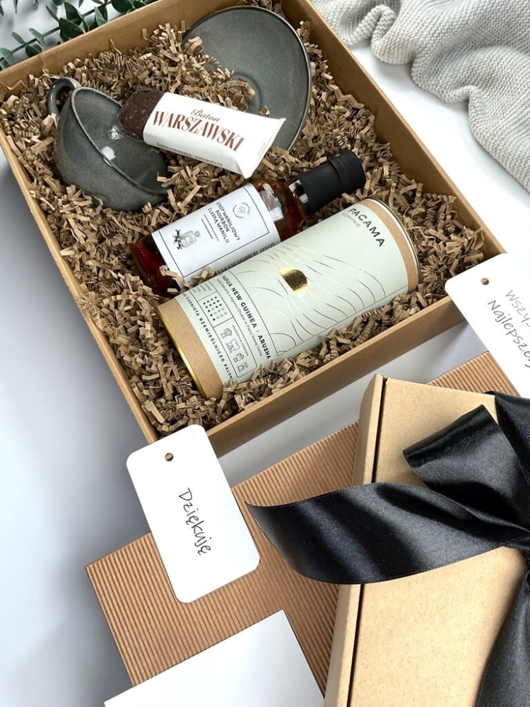 Elegancki gift box z filiżanką z kamionki, kawą premium, syropem waniliowym i batonem bezglutenowym. Idealny prezent świąteczny, biznesowy lub okolicznościowy.