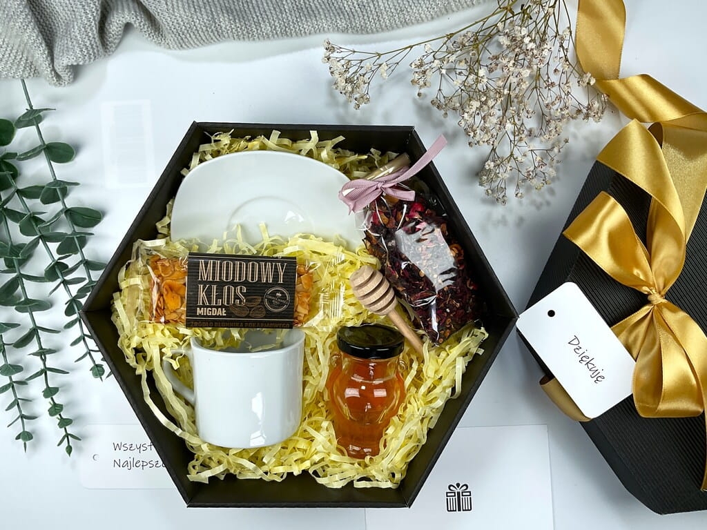 Zestaw prezentowy z filiżanką – elegancki box z białą filiżanką, naturalnym batonem miodowym z migdałami, miodem lipowym w słoiczku amfora, czerpakiem do miodu i owocową herbatą. Idealny na prezent.