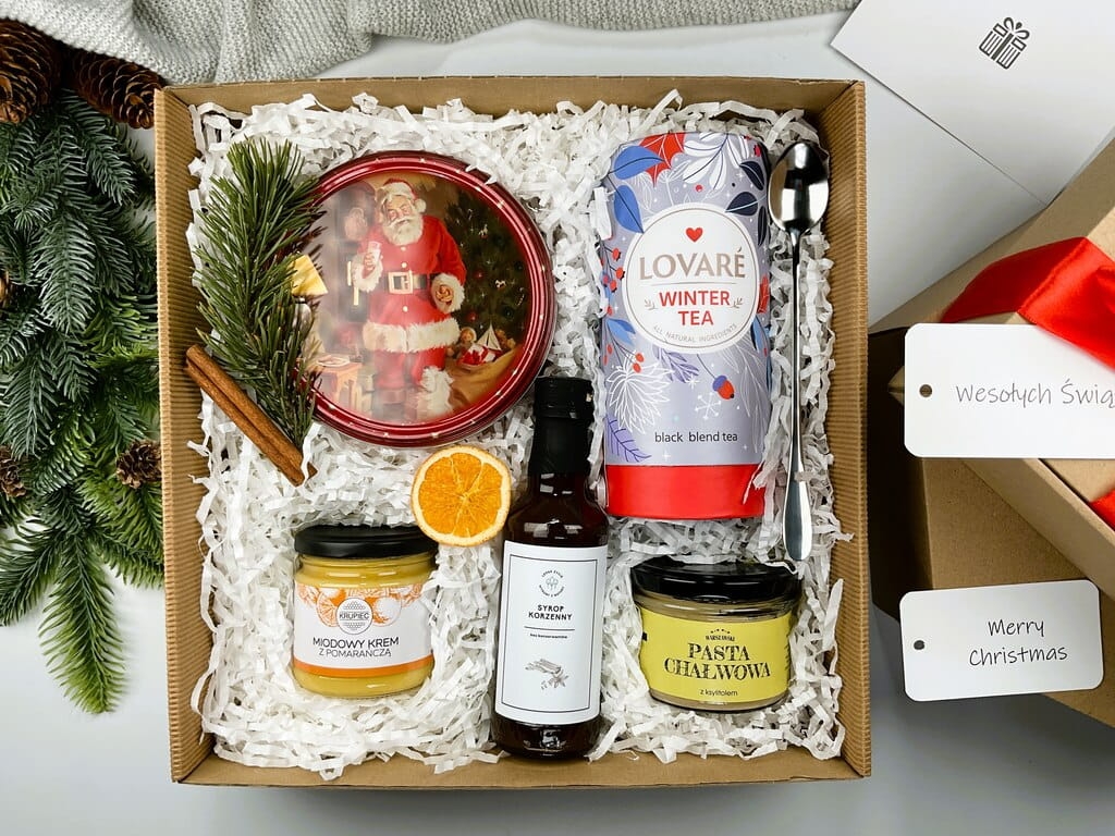 Świąteczny śniadaniowy box prezentowy – herbata, miód i ciasteczka Idealny prezent na święta: zimowa herbata, maślane duńskie ciasteczka, krem miodowy z pomarańczą i korzenny syrop do kawy. W zestawie również pasta chałwowa i srebrna łyżeczka.