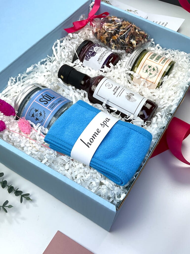 Elegancki zestaw prezentowy SPA w domu: lawendowa kąpiel, peeling cukrowy, miękka opaska spa, herbata, syrop malinowy i krem miodowy z porzeczką. Gotowy upominek premium.