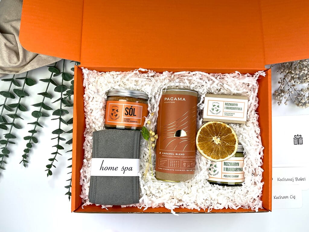 Pomarańczowy zestaw prezentowy z naturalnymi kosmetykami: sól do kąpieli rokitnik i bergamotka, peeling cukrowy rozmaryn–mandarynka, mydełko handmade, opaska spa i kawa premium.