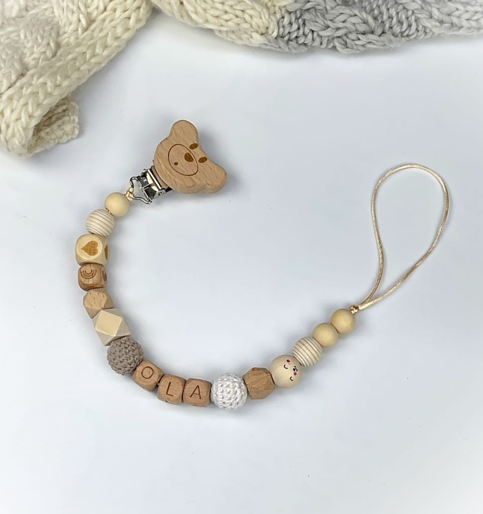 Ręcznie robiona zawieszka do smoczka z imieniem z naturalnego drewna bukowego i świerkowego. Personalizowana, ekologiczna zawieszka z drewnianych koralików, bawełnianej nitki i mocnego sznurka. Idealna na prezent dla dziecka.