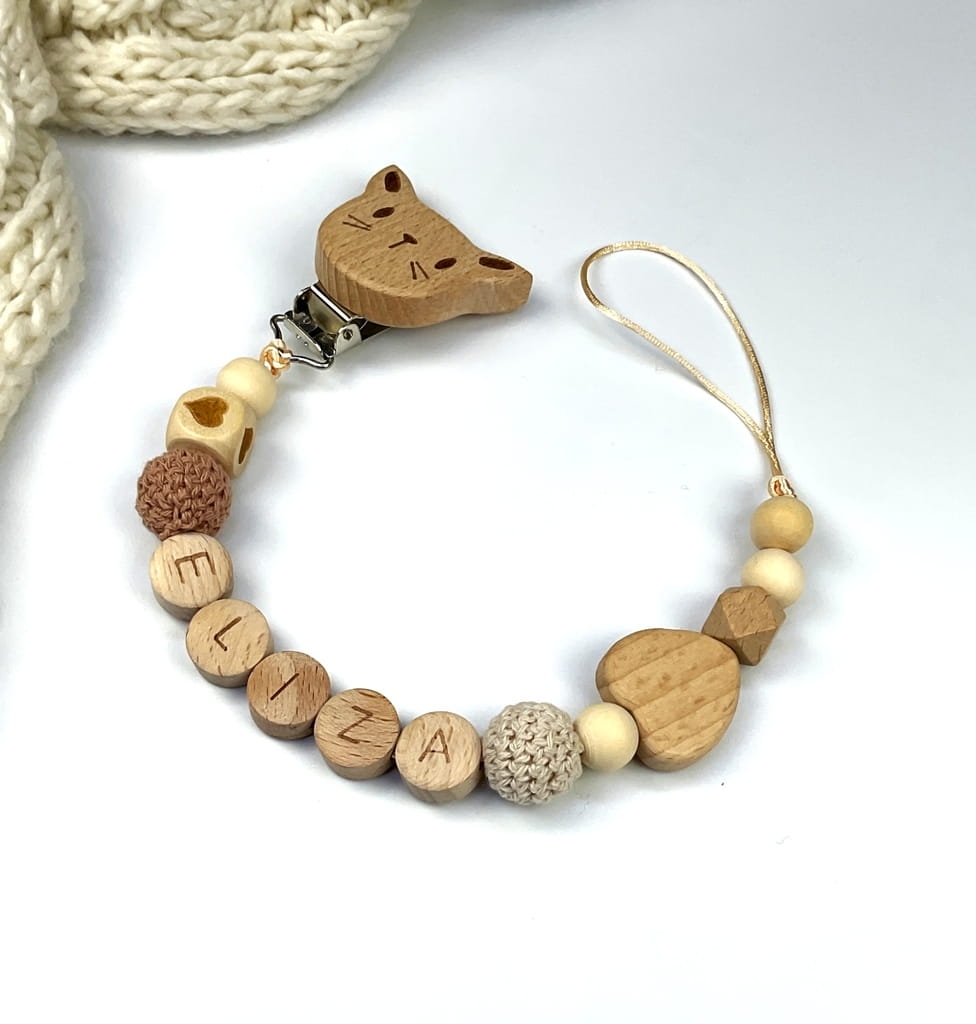 Ręcznie robiona zawieszka do smoczka z imieniem z naturalnego drewna bukowego i świerkowego. Personalizowana, ekologiczna zawieszka z drewnianych koralików, bawełnianej nitki i mocnego sznurka. Idealna na prezent dla dziecka.