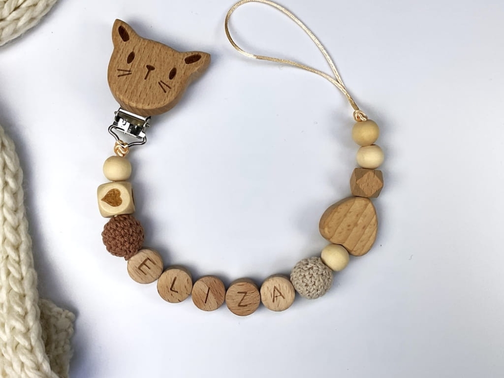 Ręcznie robiona zawieszka do smoczka z imieniem z naturalnego drewna bukowego i świerkowego. Personalizowana, ekologiczna zawieszka z drewnianych koralików, bawełnianej nitki i mocnego sznurka. Idealna na prezent dla dziecka.