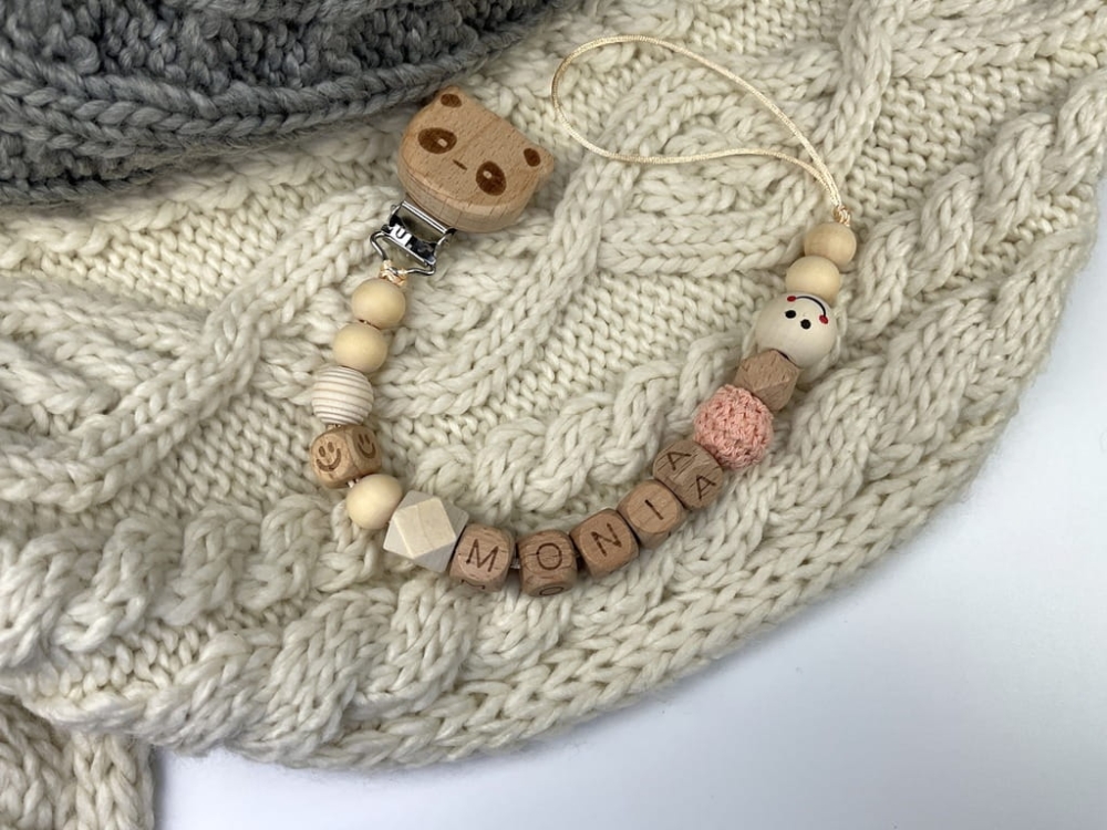 Ręcznie robiona zawieszka do smoczka z imieniem z naturalnego drewna bukowego i świerkowego. Personalizowana, ekologiczna zawieszka z drewnianych koralików, bawełnianej nitki i mocnego sznurka. Idealna na prezent dla dziecka.