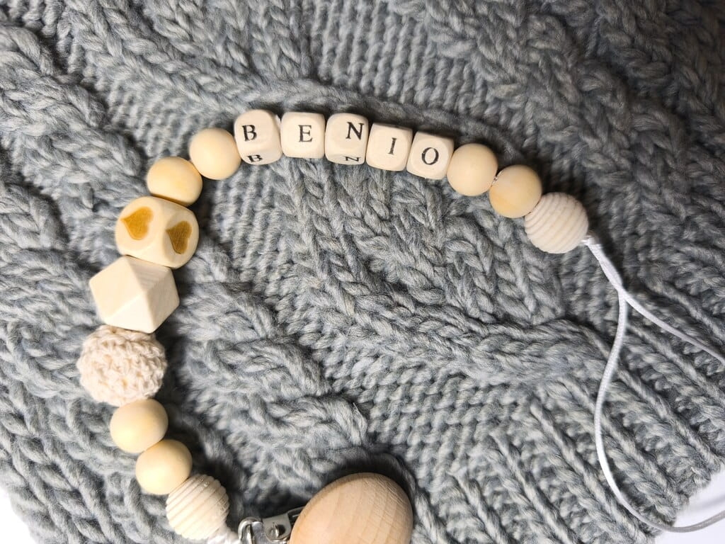 Ręcznie robiona zawieszka do smoczka z imieniem z naturalnego drewna bukowego i świerkowego. Personalizowana, ekologiczna zawieszka z drewnianych koralików, bawełnianej nitki i mocnego sznurka. Idealna na prezent dla dziecka.