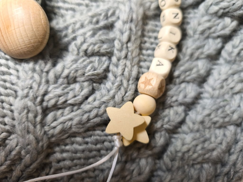 Ręcznie robiona zawieszka do smoczka z imieniem z naturalnego drewna bukowego i świerkowego. Personalizowana, ekologiczna zawieszka z drewnianych koralików, bawełnianej nitki i mocnego sznurka. Idealna na prezent dla dziecka.