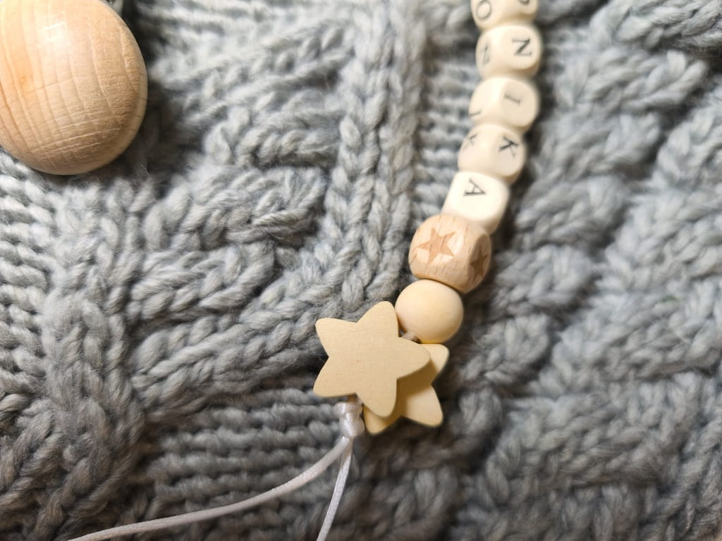 Ręcznie robiona zawieszka do smoczka z imieniem z naturalnego drewna bukowego i świerkowego. Personalizowana, ekologiczna zawieszka z drewnianych koralików, bawełnianej nitki i mocnego sznurka. Idealna na prezent dla dziecka.