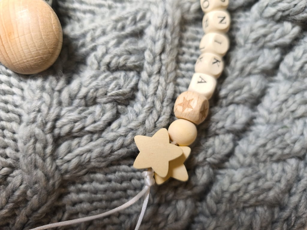 Ręcznie robiona zawieszka do smoczka z imieniem z naturalnego drewna bukowego i świerkowego. Personalizowana, ekologiczna zawieszka z drewnianych koralików, bawełnianej nitki i mocnego sznurka. Idealna na prezent dla dziecka.