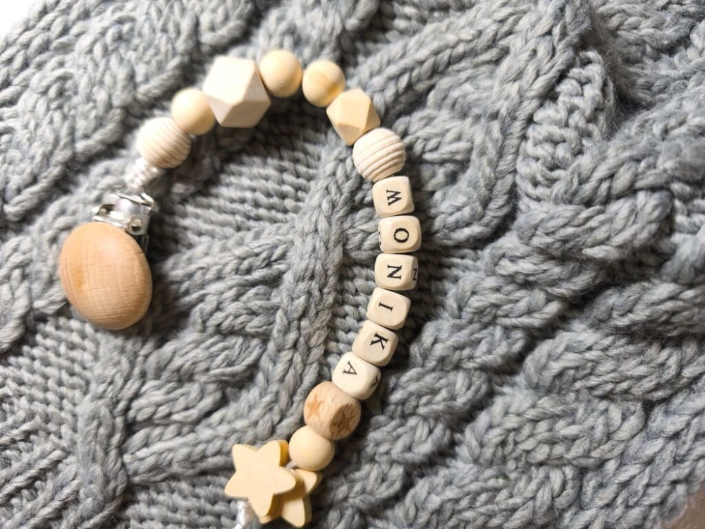 Ręcznie robiona zawieszka do smoczka z imieniem z naturalnego drewna bukowego i świerkowego. Personalizowana, ekologiczna zawieszka z drewnianych koralików, bawełnianej nitki i mocnego sznurka. Idealna na prezent dla dziecka.