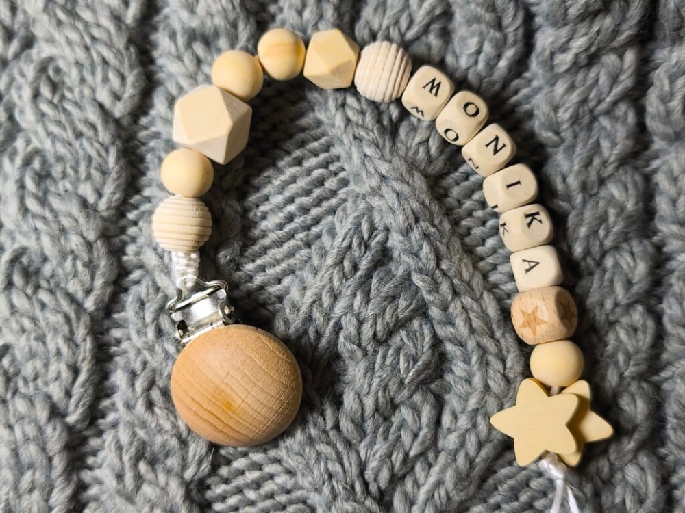 Ręcznie robiona zawieszka do smoczka z imieniem z naturalnego drewna bukowego i świerkowego. Personalizowana, ekologiczna zawieszka z drewnianych koralików, bawełnianej nitki i mocnego sznurka. Idealna na prezent dla dziecka.