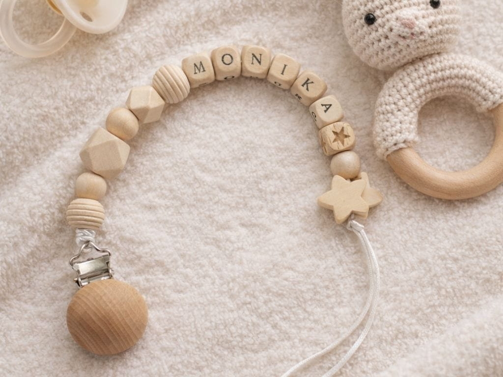 Ręcznie robiona zawieszka do smoczka z imieniem z naturalnego drewna bukowego i świerkowego. Personalizowana, ekologiczna zawieszka z drewnianych koralików, bawełnianej nitki i mocnego sznurka. Idealna na prezent dla dziecka.
