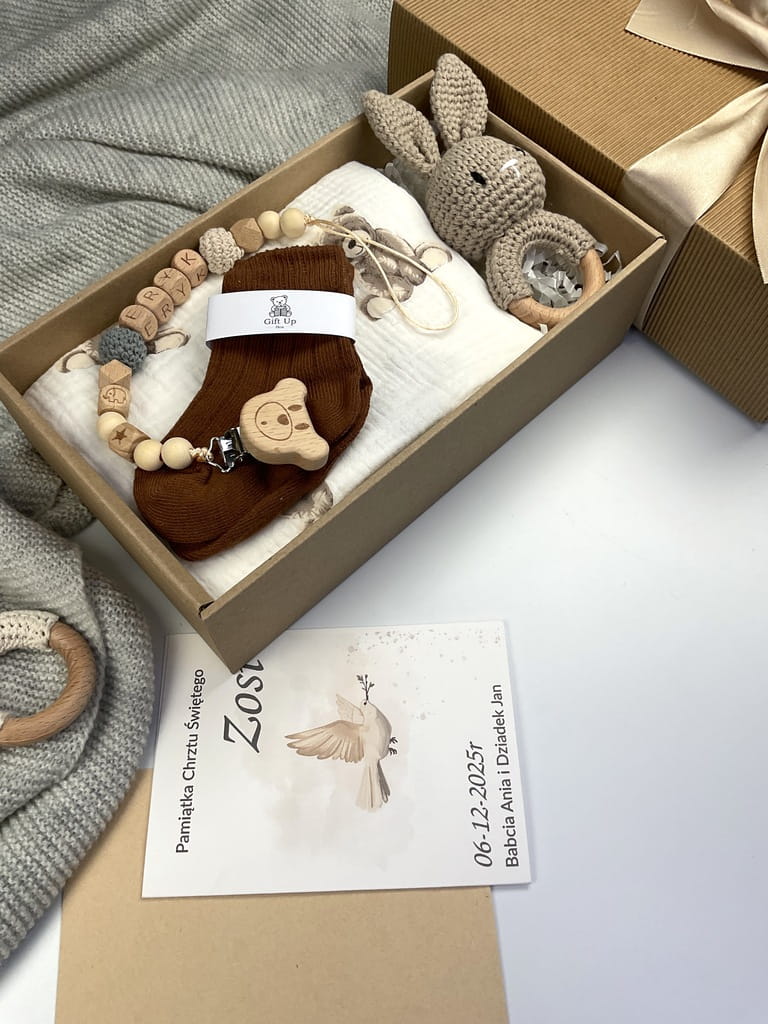 Zestaw prezentowy na chrzest dla chłopca: muślinowa pieluszka, ręcznie robiona grzechotka, zawieszka na smoczek, drewniana zawieszka z imieniem, skarpetki i personalizowana kartka.