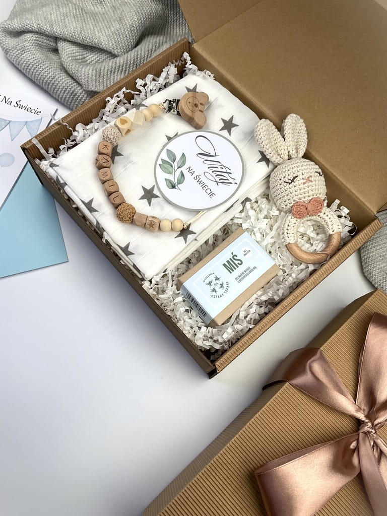 Zestaw prezentowy na chrzest dla chłopca: muślinowa pieluszka, ręcznie robiona grzechotka, zawieszka na smoczek, drewniana zawieszka z imieniem, skarpetki i personalizowana kartka.