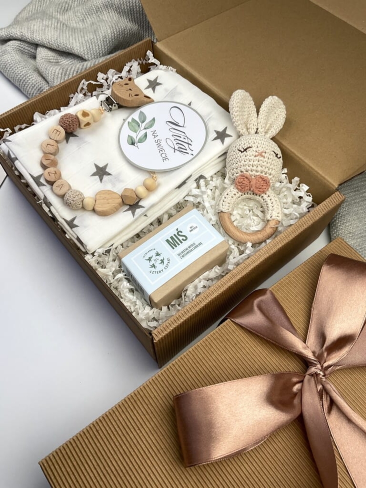 Zestaw prezentowy na chrzest dla chłopca: muślinowa pieluszka, ręcznie robiona grzechotka, zawieszka na smoczek, drewniana zawieszka z imieniem, skarpetki i personalizowana kartka.