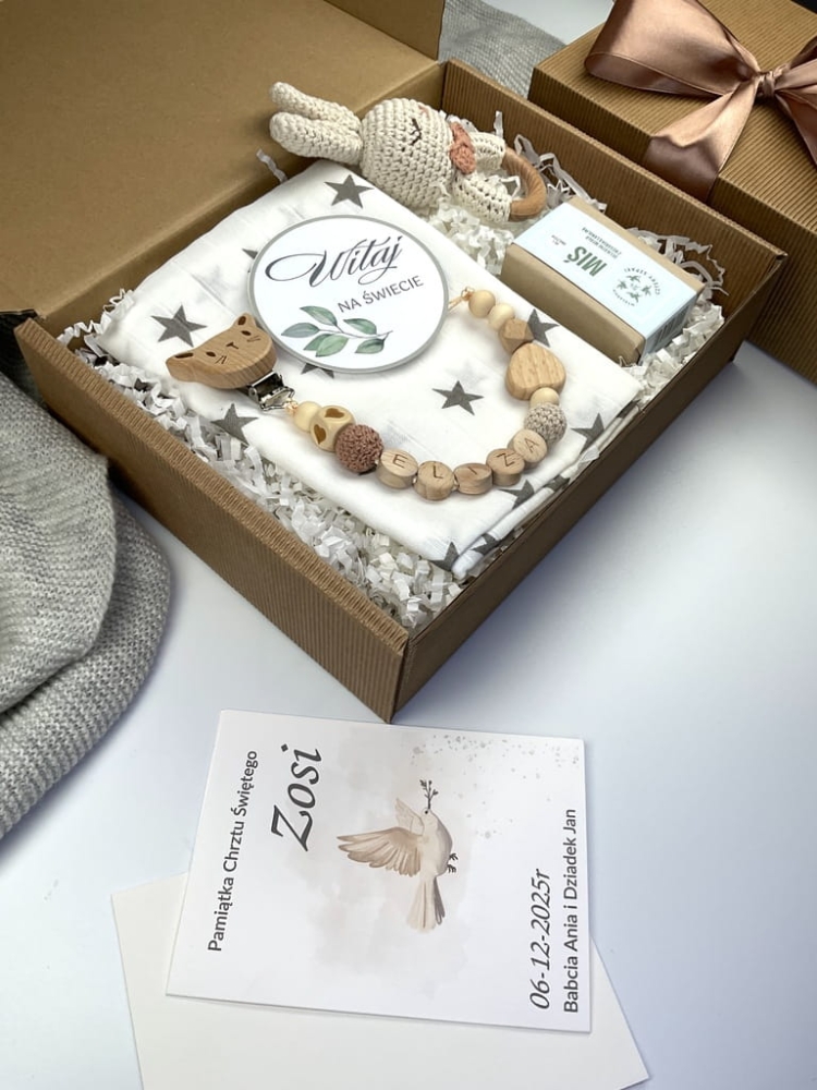 Zestaw prezentowy na chrzest dla chłopca: muślinowa pieluszka, ręcznie robiona grzechotka, zawieszka na smoczek, drewniana zawieszka z imieniem, skarpetki i personalizowana kartka.