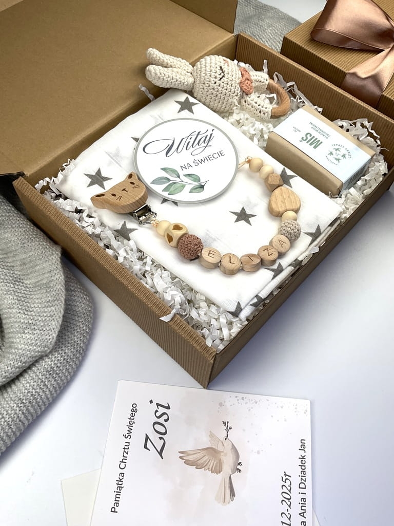 Zestaw prezentowy na chrzest dla chłopca: muślinowa pieluszka, ręcznie robiona grzechotka, zawieszka na smoczek, drewniana zawieszka z imieniem, skarpetki i personalizowana kartka.