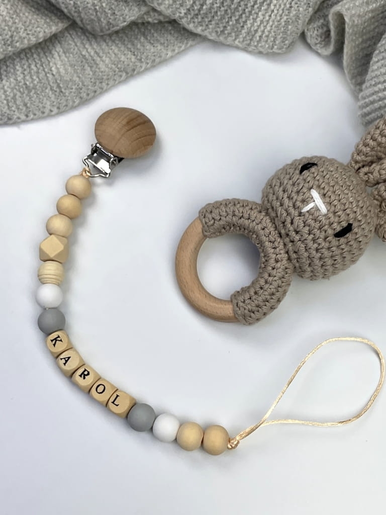 Ręcznie robiona zawieszka do smoczka z imieniem z naturalnego drewna bukowego i świerkowego. Personalizowana, ekologiczna zawieszka z drewnianych koralików, bawełnianej nitki i mocnego sznurka. Idealna na prezent dla dziecka.