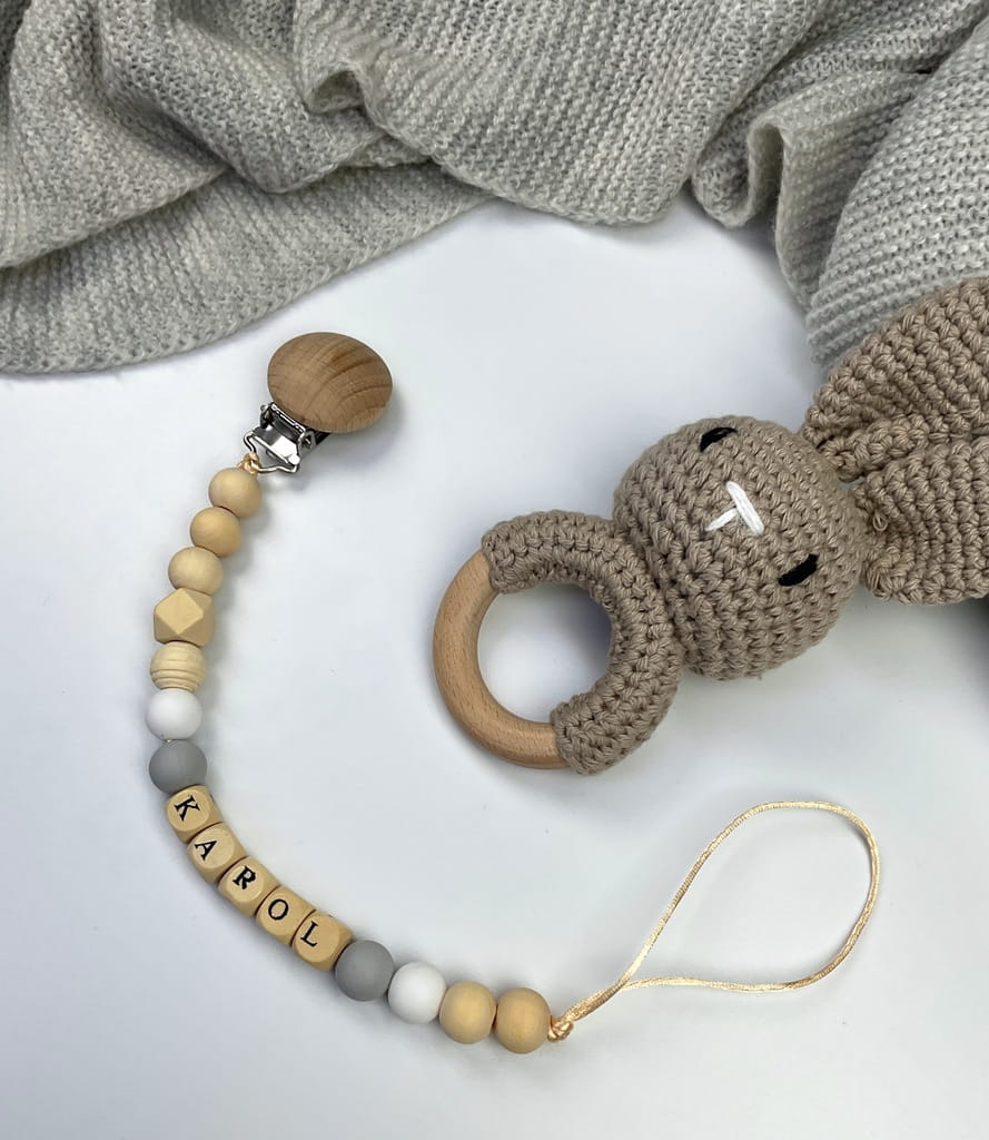 Ręcznie robiona zawieszka do smoczka z imieniem z naturalnego drewna bukowego i świerkowego. Personalizowana, ekologiczna zawieszka z drewnianych koralików, bawełnianej nitki i mocnego sznurka. Idealna na prezent dla dziecka.