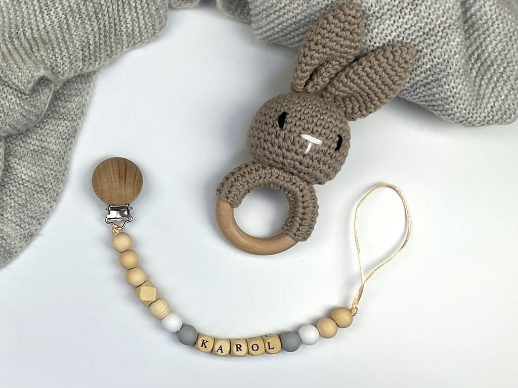 Ręcznie robiona zawieszka do smoczka z imieniem z naturalnego drewna bukowego i świerkowego. Personalizowana, ekologiczna zawieszka z drewnianych koralików, bawełnianej nitki i mocnego sznurka. Idealna na prezent dla dziecka.
