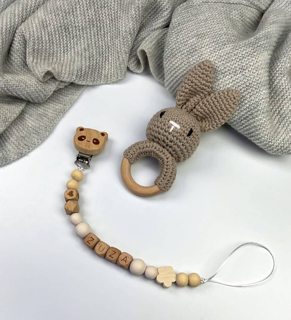 Ręcznie robiona zawieszka do smoczka z drewnianych koralików. Personalizowana imieniem dziecka, bezpieczna i stylowa. Idealny dodatek dla niemowląt i wyjątkowy pomysł na prezent.