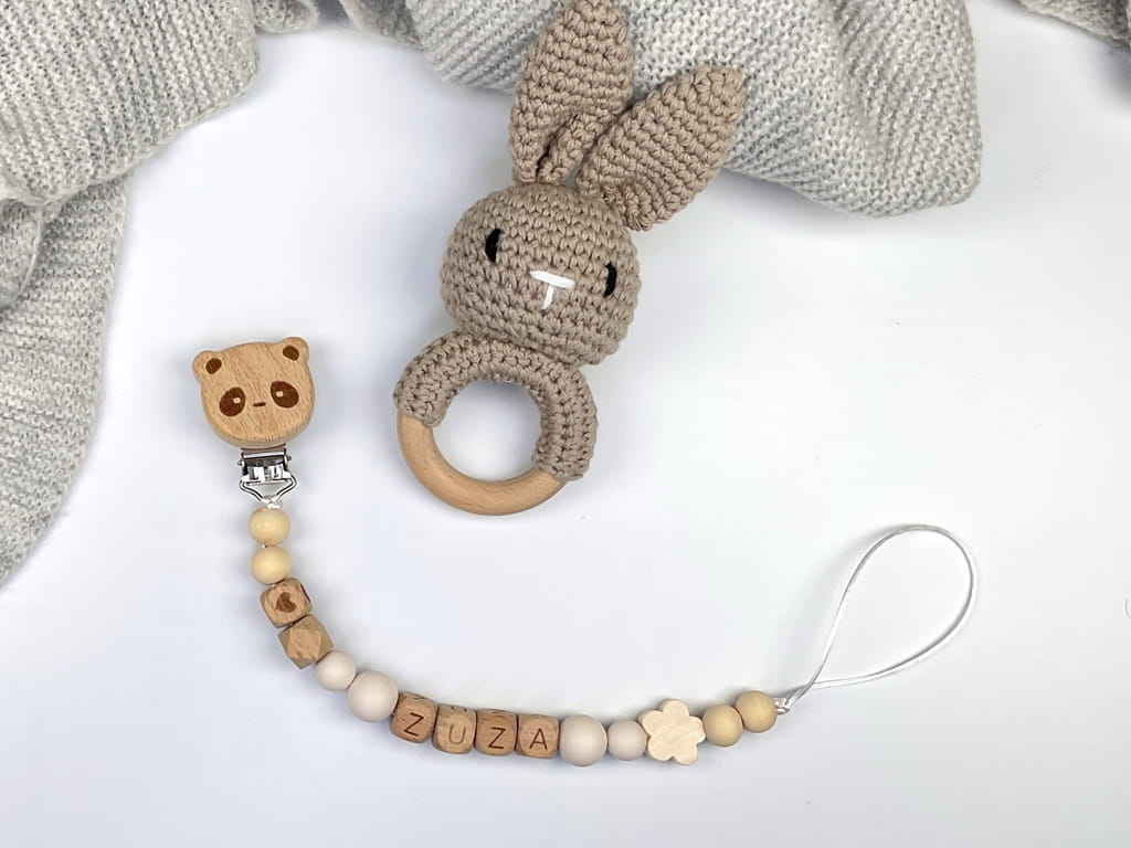 Ręcznie robiona zawieszka do smoczka z drewnianych koralików. Personalizowana imieniem dziecka, bezpieczna i stylowa. Idealny dodatek dla niemowląt i wyjątkowy pomysł na prezent.