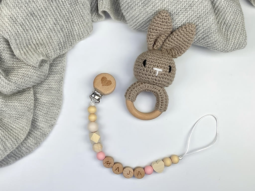 Ręcznie robiona zawieszka do smoczka z drewnianych koralików. Personalizowana imieniem dziecka, bezpieczna i stylowa. Idealny dodatek dla niemowląt i wyjątkowy pomysł na prezent.