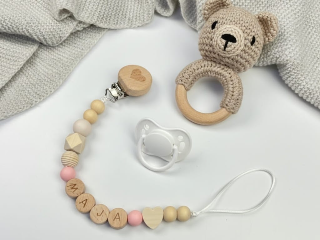 Ręcznie robiona zawieszka do smoczka z drewnianych koralików. Personalizowana imieniem dziecka, bezpieczna i stylowa. Idealny dodatek dla niemowląt i wyjątkowy pomysł na prezent.