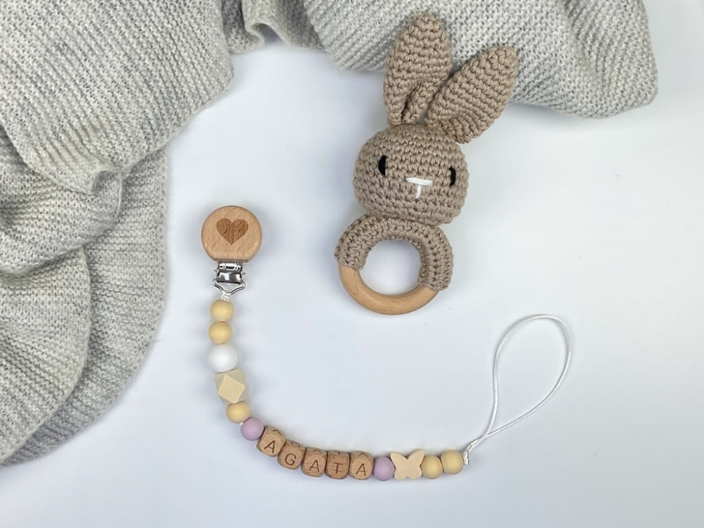 Ręcznie robiona zawieszka do smoczka z drewnianych koralików. Personalizowana imieniem dziecka, bezpieczna i stylowa. Idealny dodatek dla niemowląt i wyjątkowy pomysł na prezent.