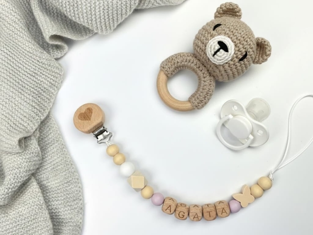 Ręcznie robiona zawieszka do smoczka z drewnianych koralików. Personalizowana imieniem dziecka, bezpieczna i stylowa. Idealny dodatek dla niemowląt i wyjątkowy pomysł na prezent.