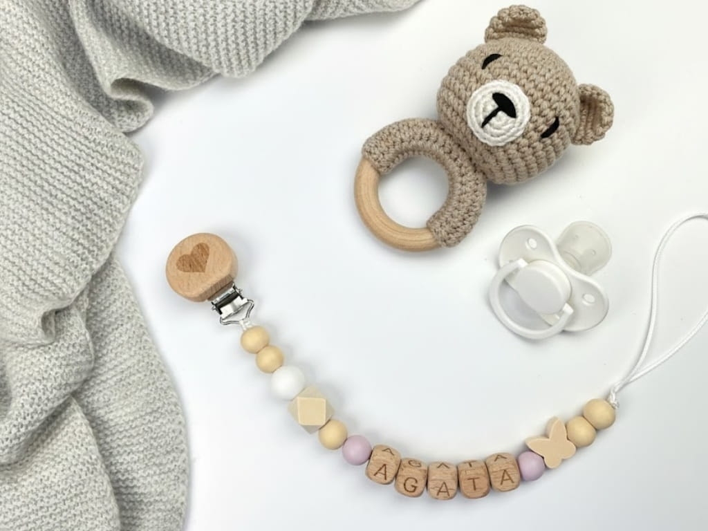 Ręcznie robiona zawieszka do smoczka z drewnianych koralików. Personalizowana imieniem dziecka, bezpieczna i stylowa. Idealny dodatek dla niemowląt i wyjątkowy pomysł na prezent.