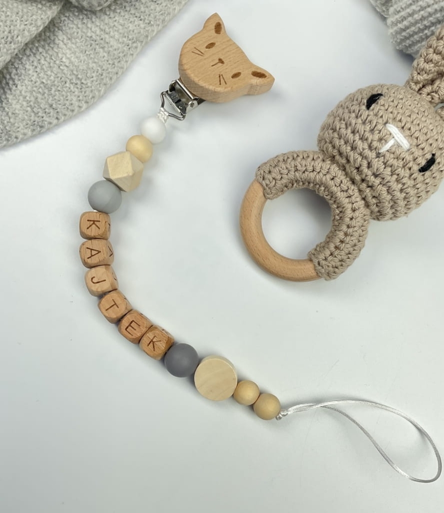 Ręcznie robiona zawieszka do smoczka z drewnianych koralików. Personalizowana imieniem dziecka, bezpieczna i stylowa. Idealny dodatek dla niemowląt i wyjątkowy pomysł na prezent.