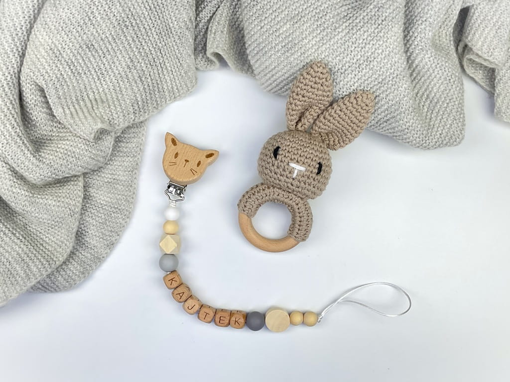 Ręcznie robiona zawieszka do smoczka z drewnianych koralików. Personalizowana imieniem dziecka, bezpieczna i stylowa. Idealny dodatek dla niemowląt i wyjątkowy pomysł na prezent.