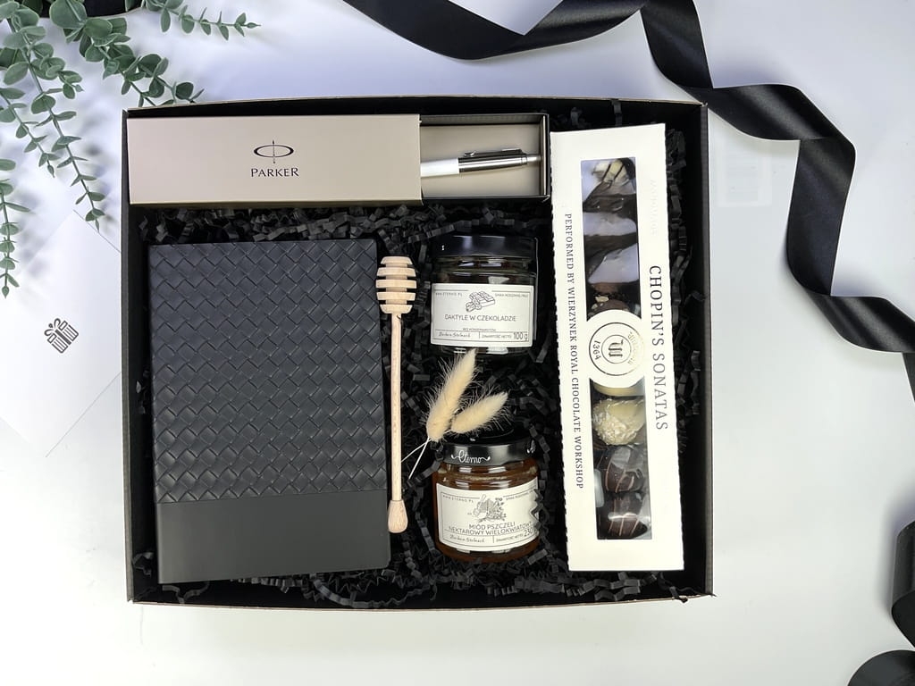Elegancki zestaw prezentowy z długopisem Parker i skórzanym notatnikiem. W komplecie ręcznie robione pralinki, naturalny miód i daktyle w czekoladzie. Idealny upominek biznesowy lub premium dla bliskiej osoby