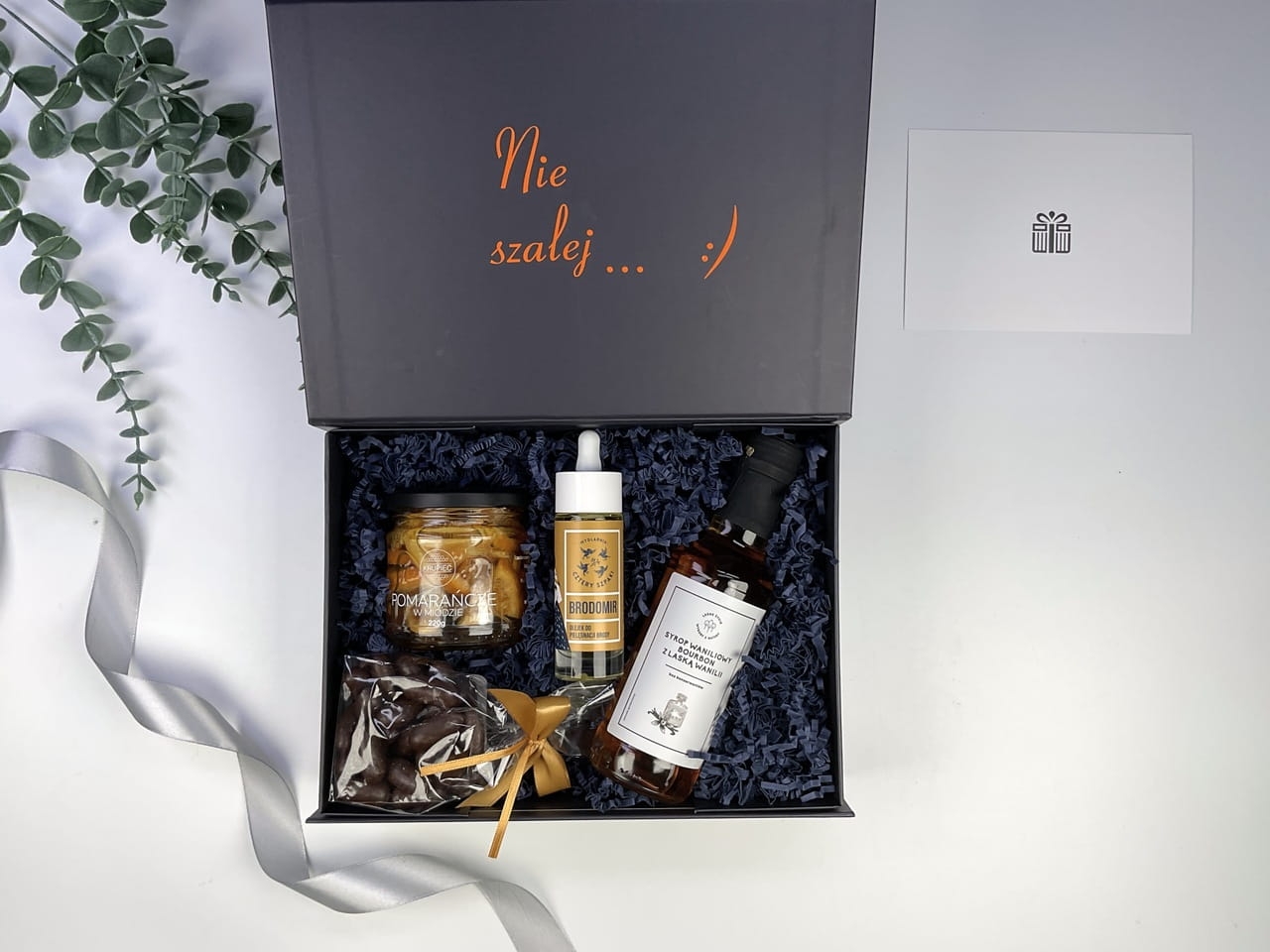Luksusowy box personalizowany z wstążką i personalizowanym napisem na i w środku. Olejek do brody, syrop waniliowy, pomarańcze w miodzie i czekolada rzemieślnicza.