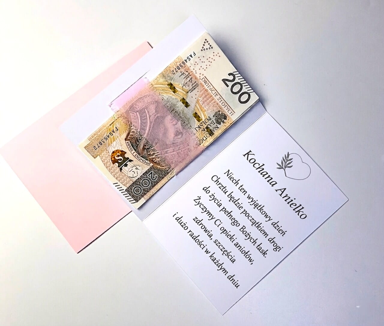 Pamiątka Chrztu Świętego z różową szyfonową wstążką i suszkami.