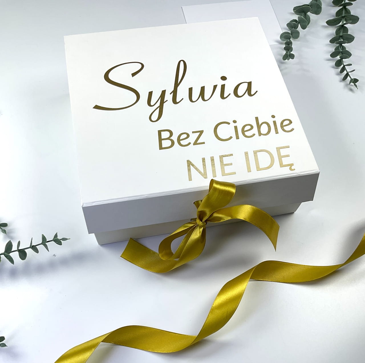 Zestaw prezentowy dla druhny z personalizacją. Białe pudełko, złota wstążka, szampan i kieliszek z imieniem na zamówienie.