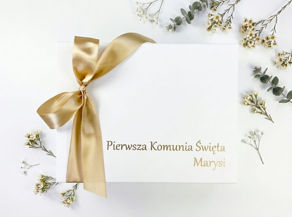 Białe pudełko magnetyczne na Komunię ze złotym napisem „Pierwsza Komunia Święta Tymka”. Personalizowane pudełko z folii Oracal i złotą kokardą.