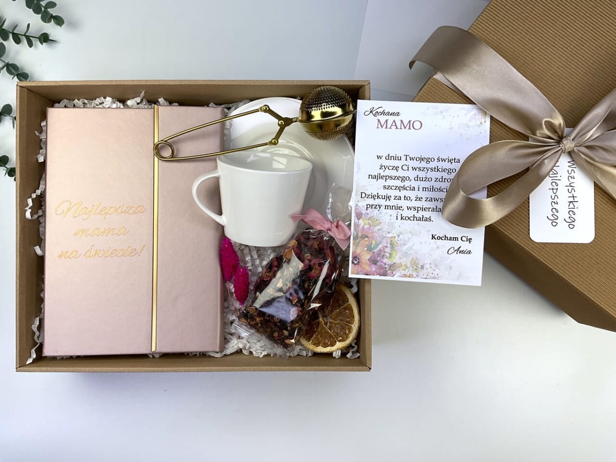 Prezent na Dzień Mamy z personalizowanym notesem, białą filiżanką porcelanową i herbatą. Gotowy box w pudełku ryflowanym z różową wstążką.