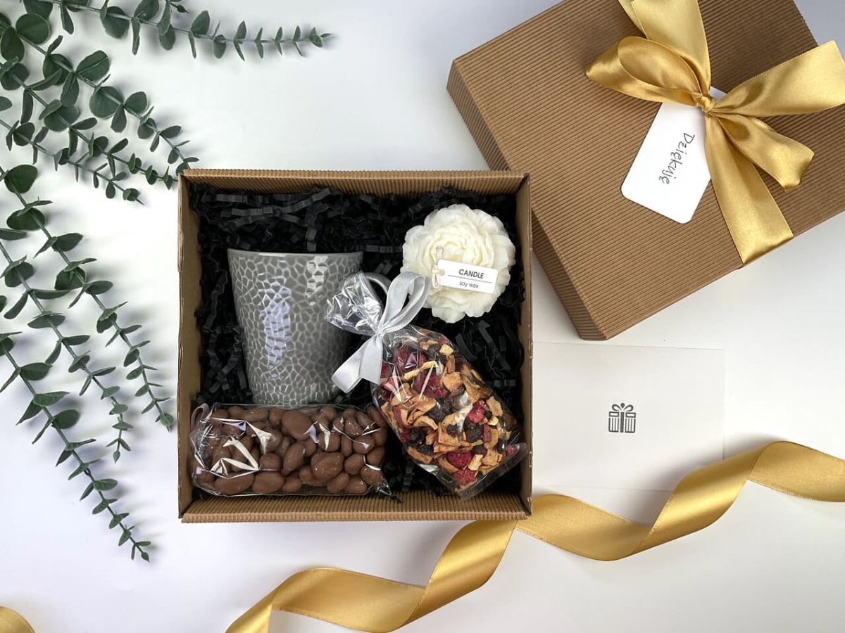 zestaw box prezentowy na dzień nauczyciela imieniny lub urodziny który zawiera szary nowoczesny kubek, ręcznie robioną naturalną świecę sojową, orzechy w mlecznej czekoladzie, herbatę z różą i lawendą