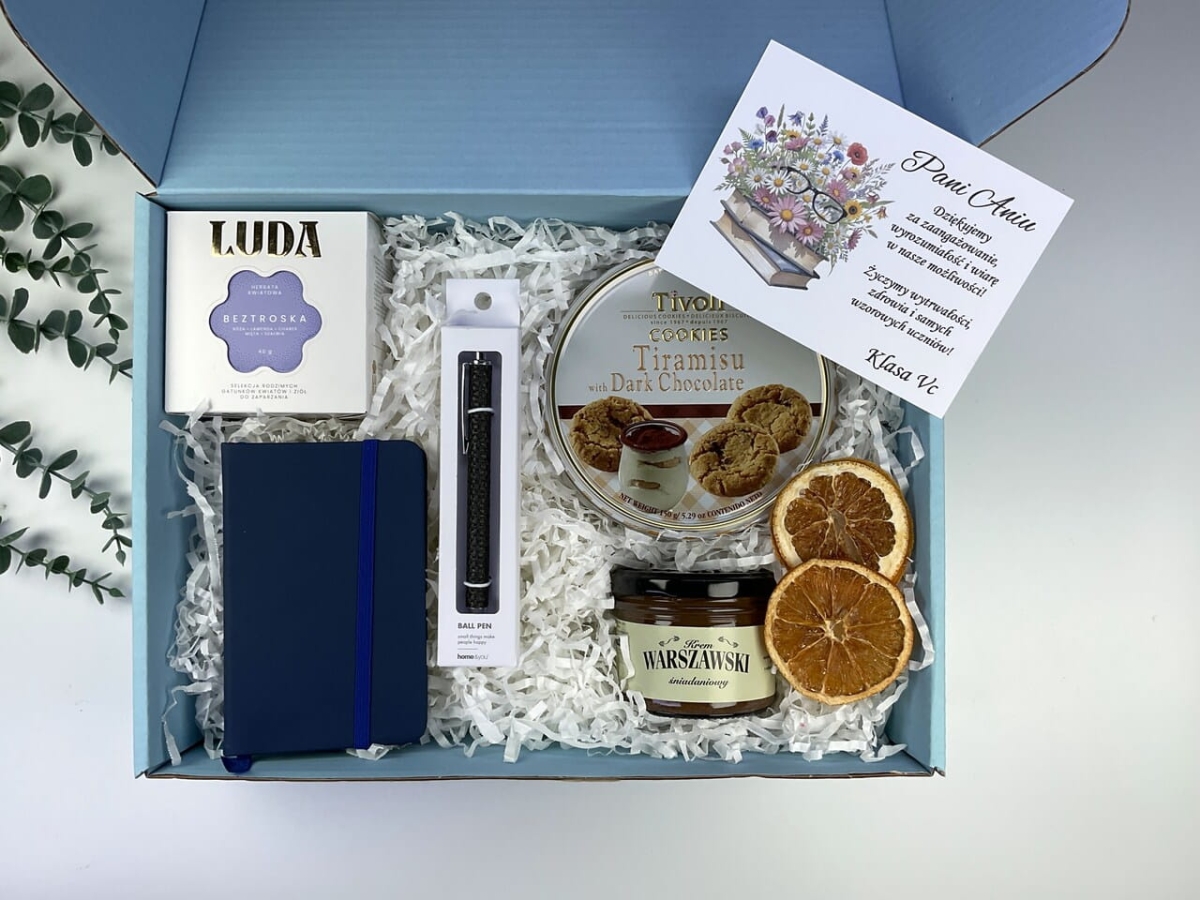 Prezent dla wychowawcy z personalizowaną kartką z życzeniami od klasy. Niebieskie pudełko upominkowe z notesem.
