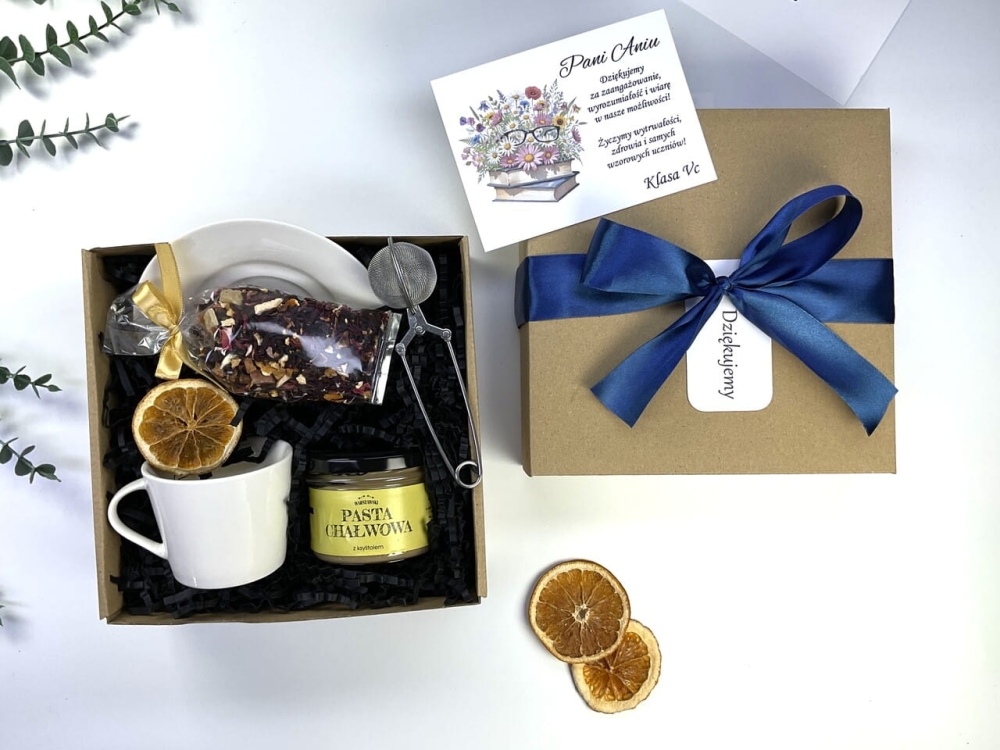 Wyjątkowy zestaw dla nauczyciela na zakończenie roku. Elegancka filiżanka, pasta chałwowa i owocowa herbata w ozdobnym pudełku z granatową wstążką i personalizowaną dedykacją od klasy. Kup teraz idealne podziękowanie!