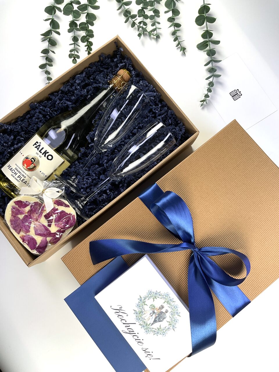 Gotowy box prezentowy dla Pary Młodej. Stylowe opakowanie, wino musujące 0%, dwa kieliszki, słodki upominek oraz kartka z możliwością personalizacji.